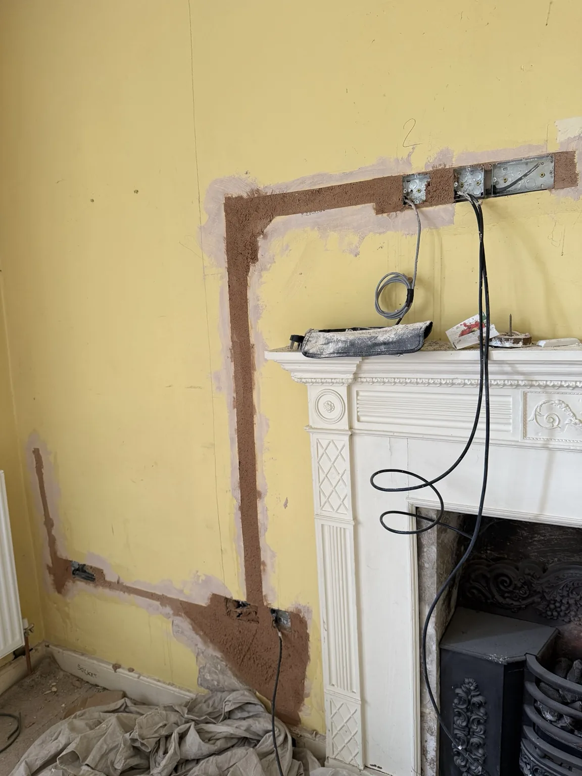 Bonded and filled cable chases around a period fireplace during the Bath rewire